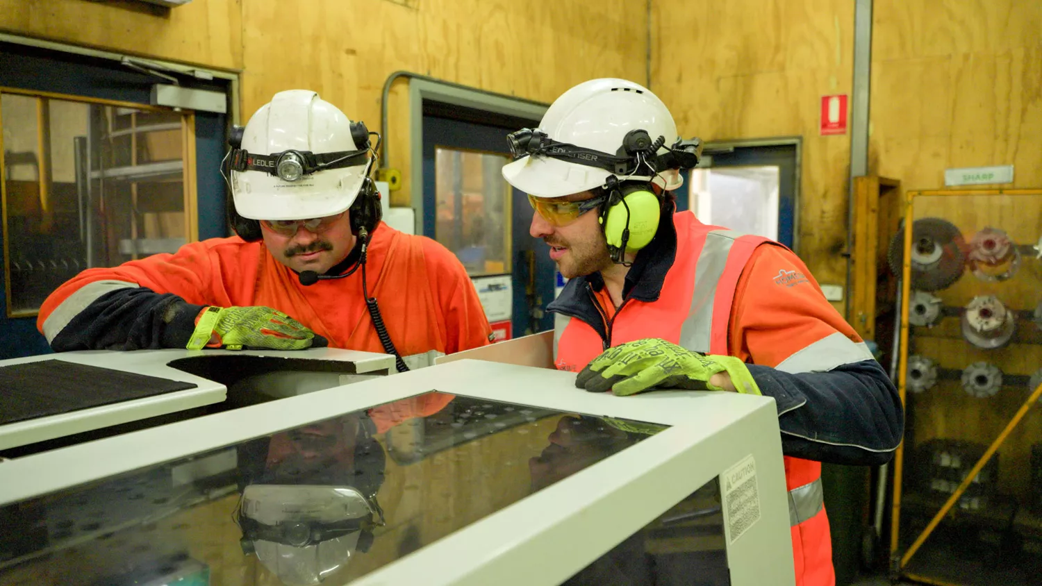  Two men in high visibility clothing and hard hats in an industrial environment.
